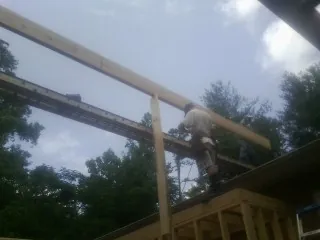Carpenter setting a ridge beam over a new addition frame — Ice Dam Removal by Roofing Brothers in Goodview