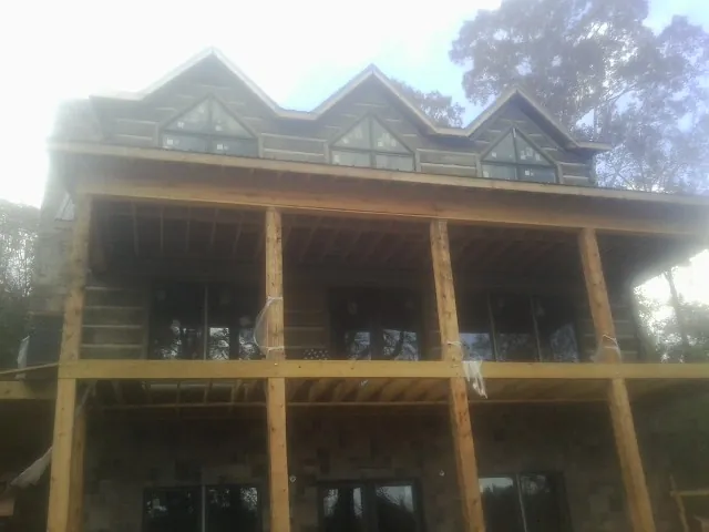 Dormers and porch framing on a large log home under construction — Roof Coating work by our crew in Goodview