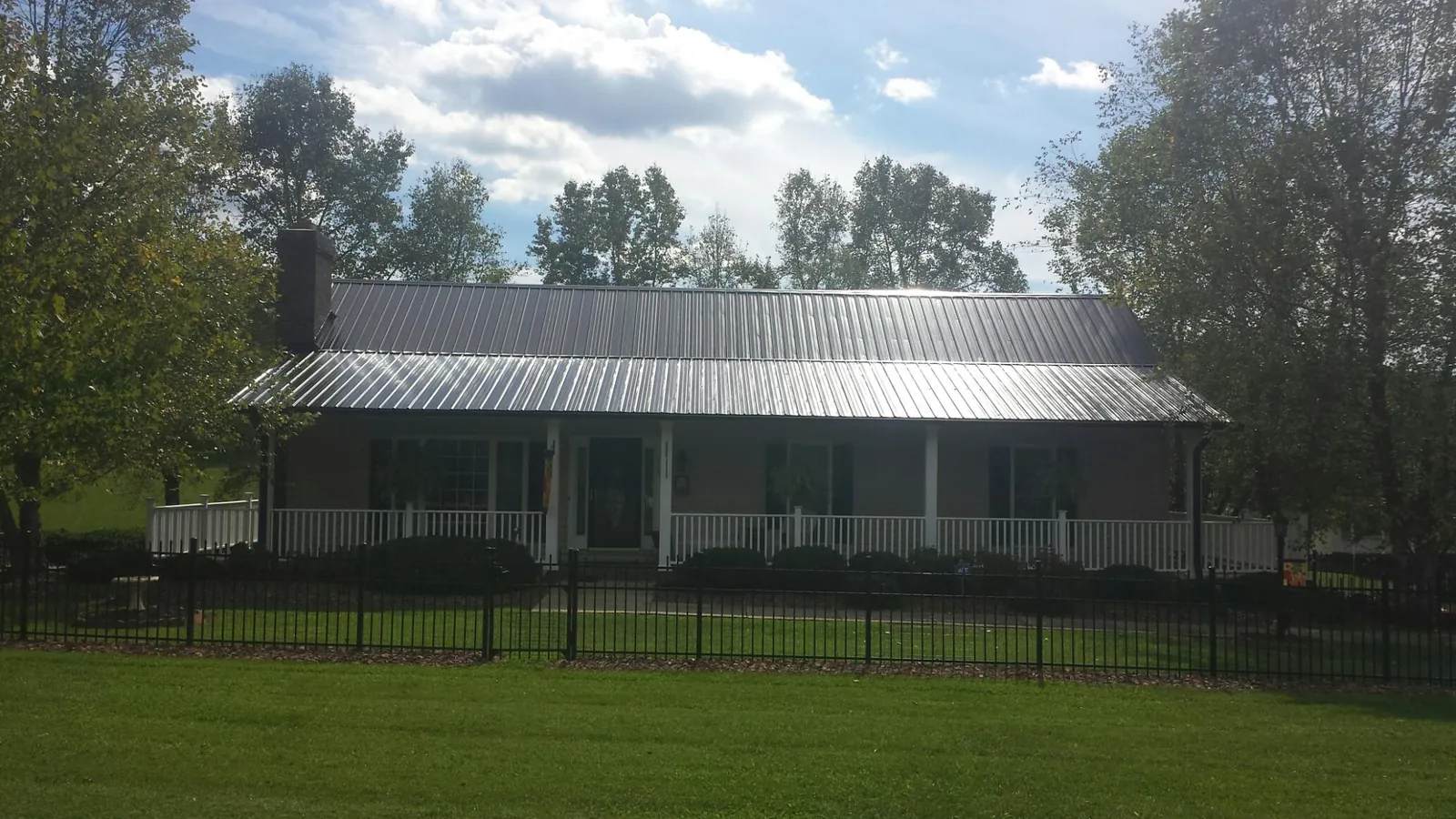 Gray metal roof on a brick ranch with a full width front porch — Gutter Guard Installation work by our crew in Goodview