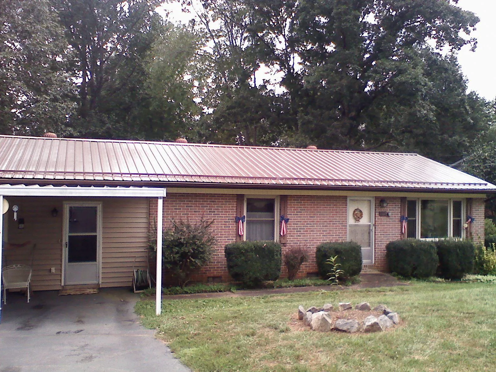 Bronze metal roof and carport on a brick ranch home — Roof Repair work by our crew in Goodview